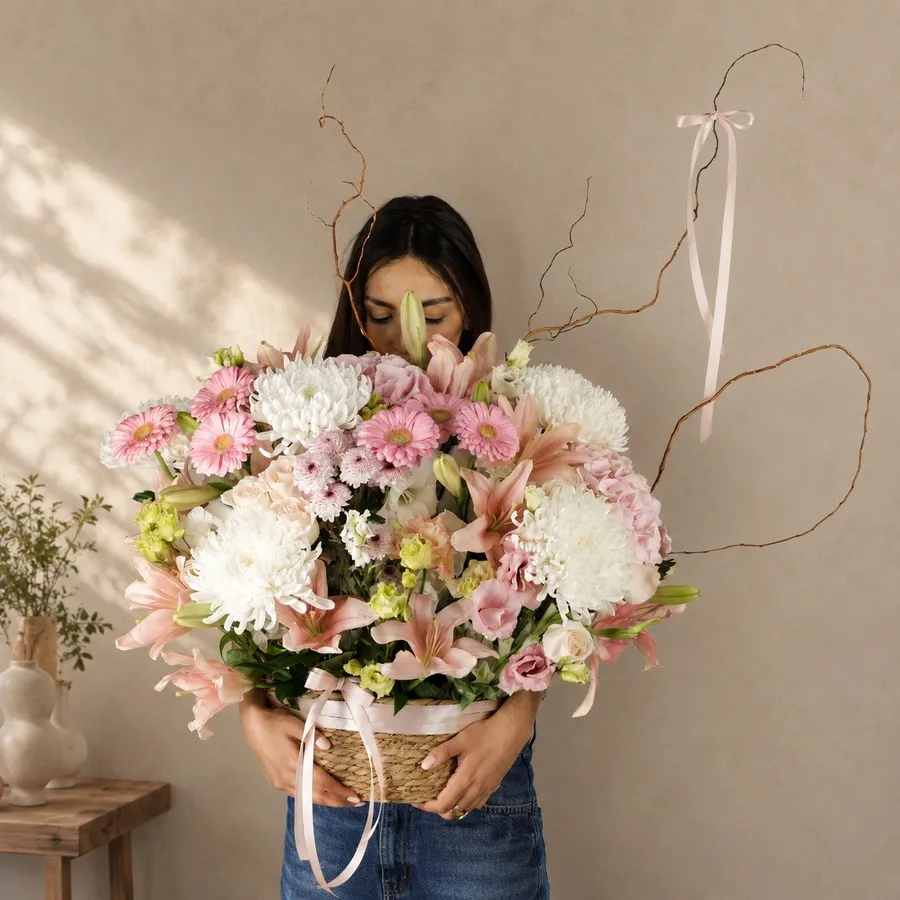 Bouquet Rose Pastel tenu à bout de bras devant un mur beige